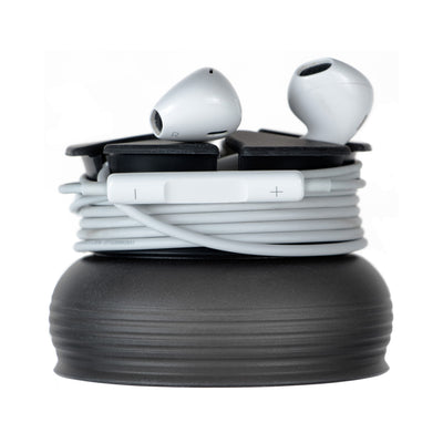 Side studio photo of a black Nest with a pair white earbuds wrapped around it.