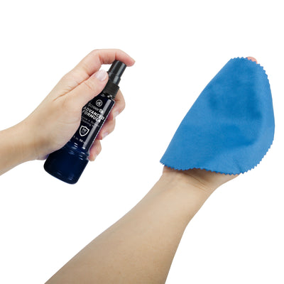 Studio photo of a pair of hands holding and spraying a bottle of ScreenDr Advanced Formula 2 fl. oz. on a blue microfiber cloth.